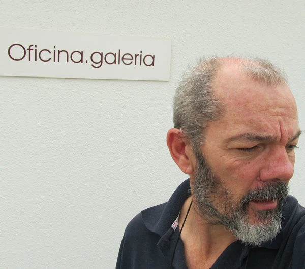 A fotografia de José Machado Pires à frente da entrada da sua loja com a placa da "oficina.galeria" atrás dele.